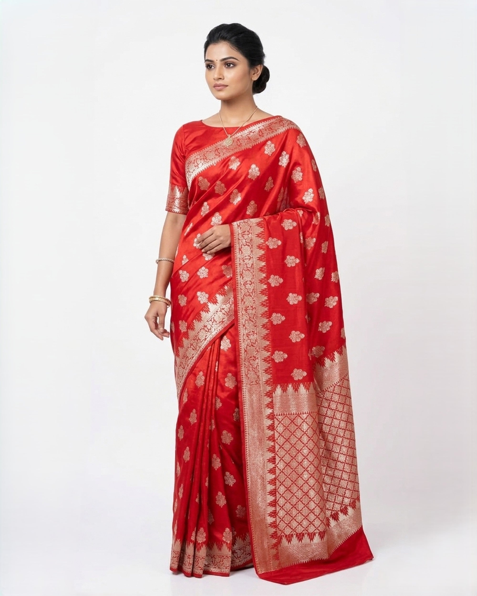 A woman wearing a vibrant red Banarasi silk saree with intricate gold zari floral patterns and a broad, decorative border, posed against a plain white background.