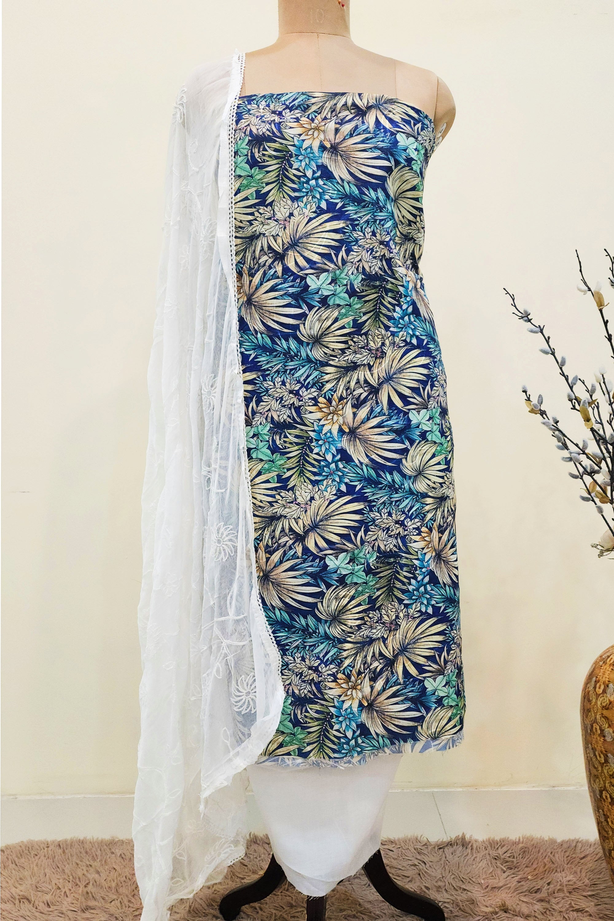 Unstitched salwar kameez set featuring a navy and beige floral printed kurta on a mannequin with a white embroidered organza dupatta draped over the shoulder.