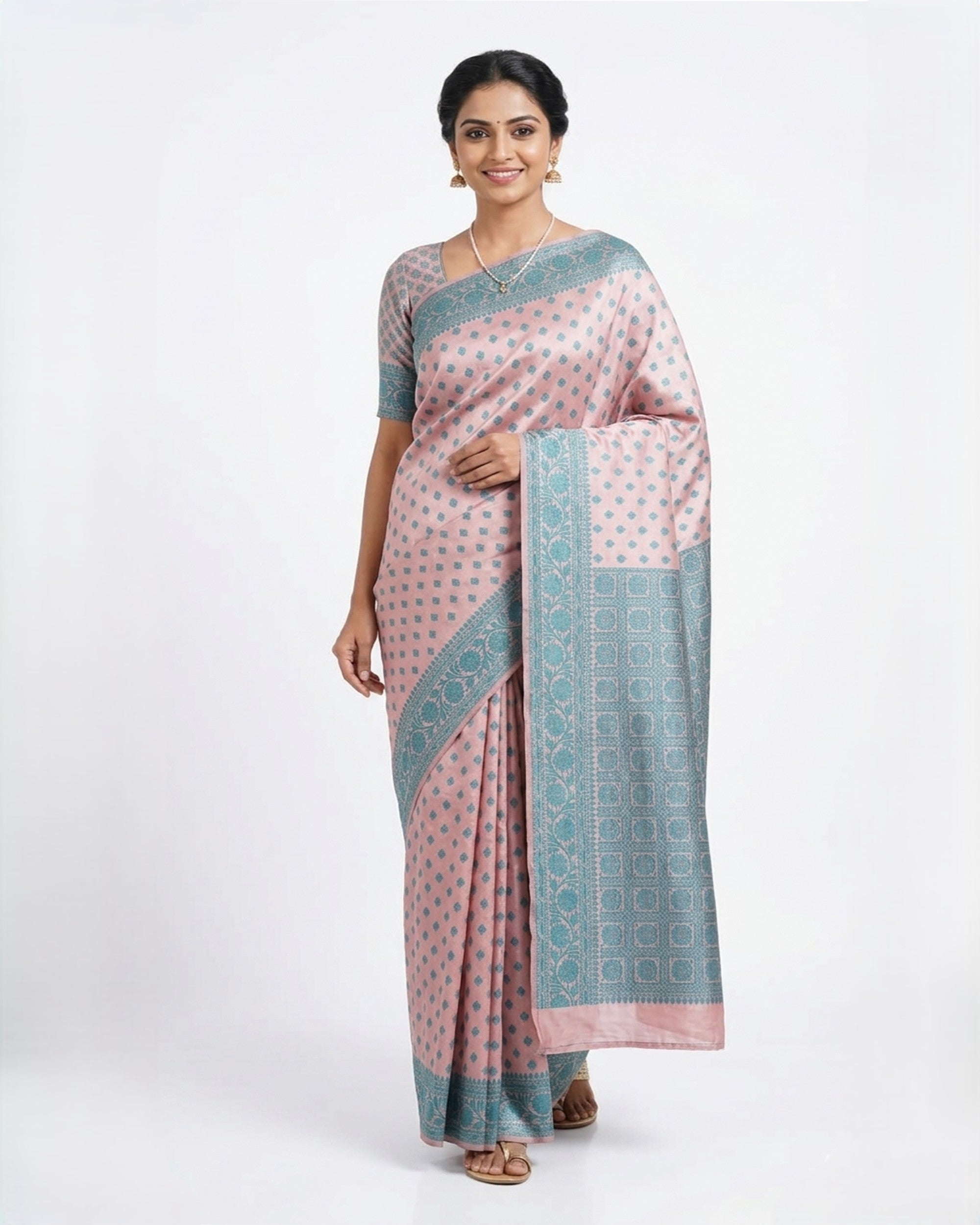 A woman gracefully modelling a baby pink & teal blue Banarasi silk blend saree from The Weaver's Shop, featuring all-over floral Zari butas, a wide teal border with intricate golden weaving, and a matching woven blouse against a white background.
