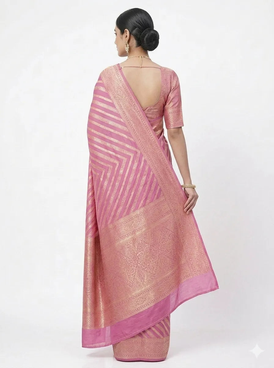 Back view of a woman wearing a Pink & Gold-Toned Striped Zari Banarasi Silk Saree, showcasing the intricate golden Zari work on the pallu, V-shaped striped patterns, and a matching silk blouse with a deep back design.
