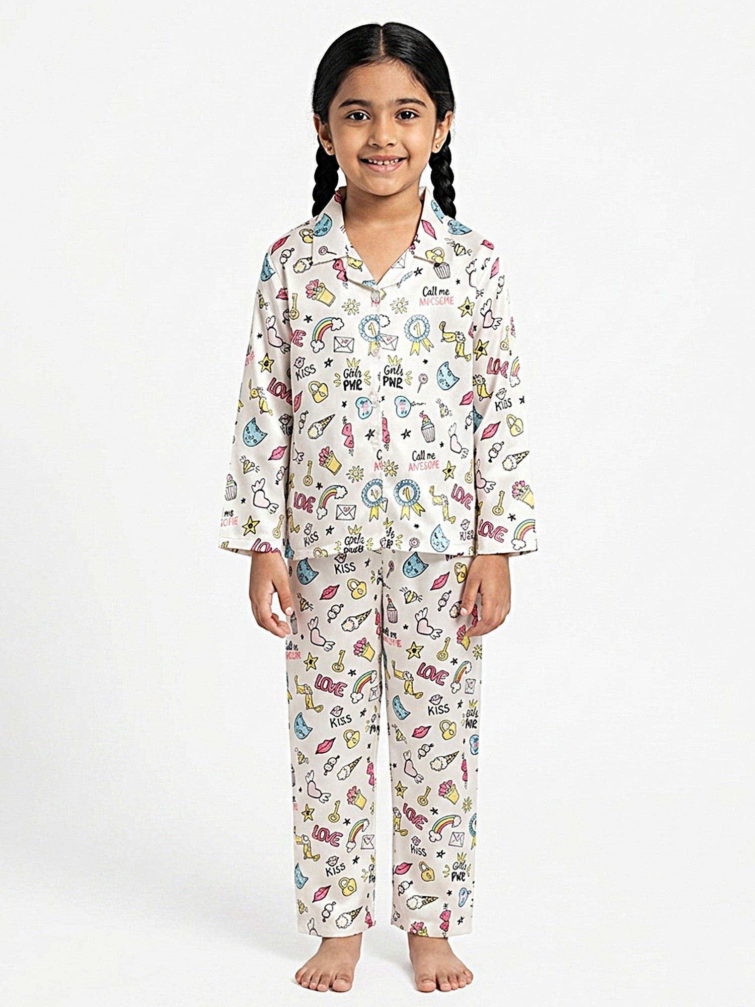 A young girl standing against a white background wearing a white satin pajama set featuring colorful prints of rainbows, cats, and "Girls PWR" text, as seen in