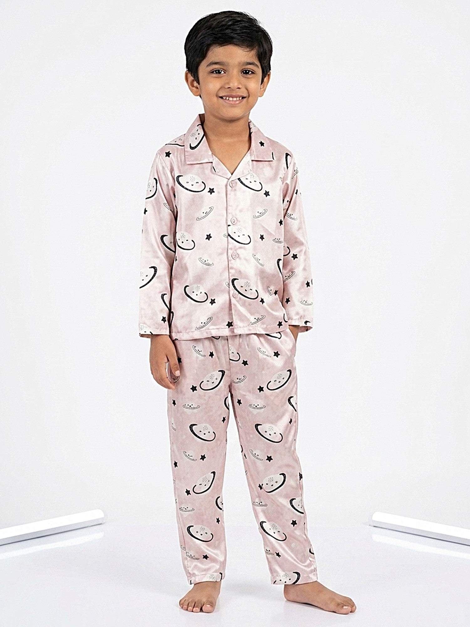 Young boy smiling while wearing a pastel pink satin full-sleeve celestial printed night suit.