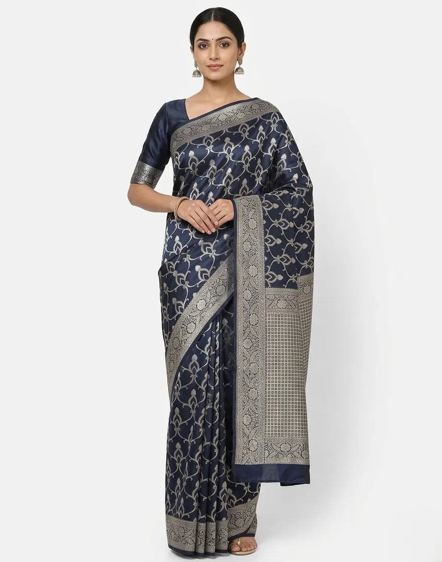 A woman wearing a navy blue art silk Banarasi saree with silver floral weaving and a decorative zari border.