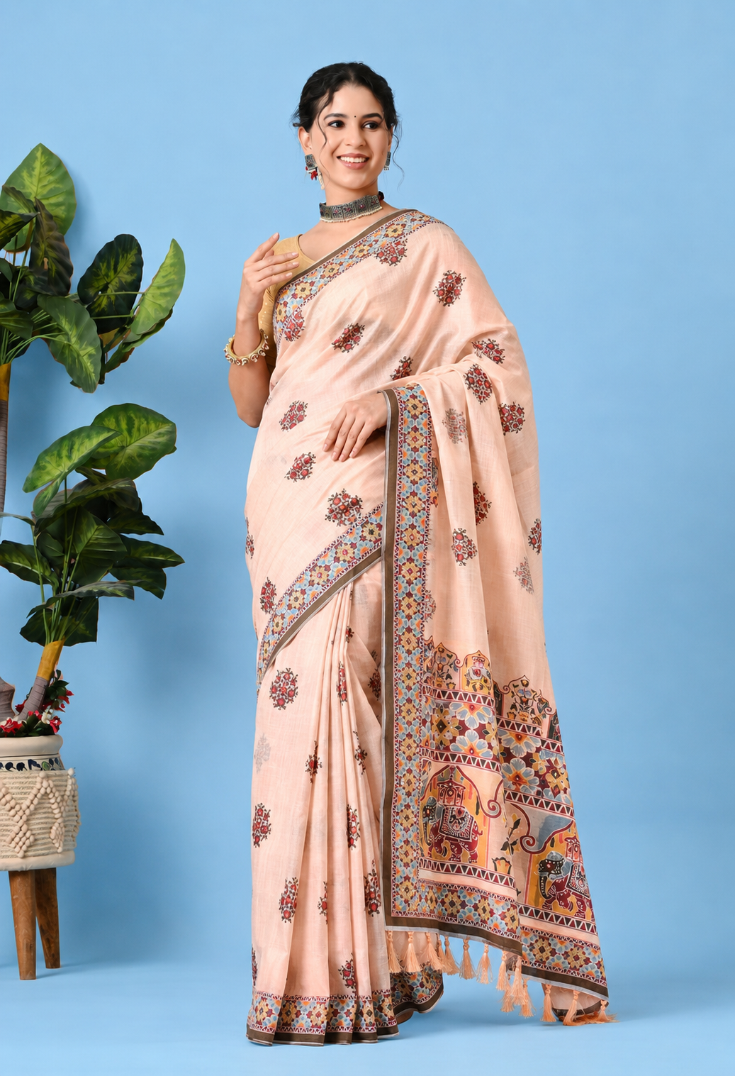 Peach cotton saree with floral prints, elephant motifs, multicolour border and tassel detailing.