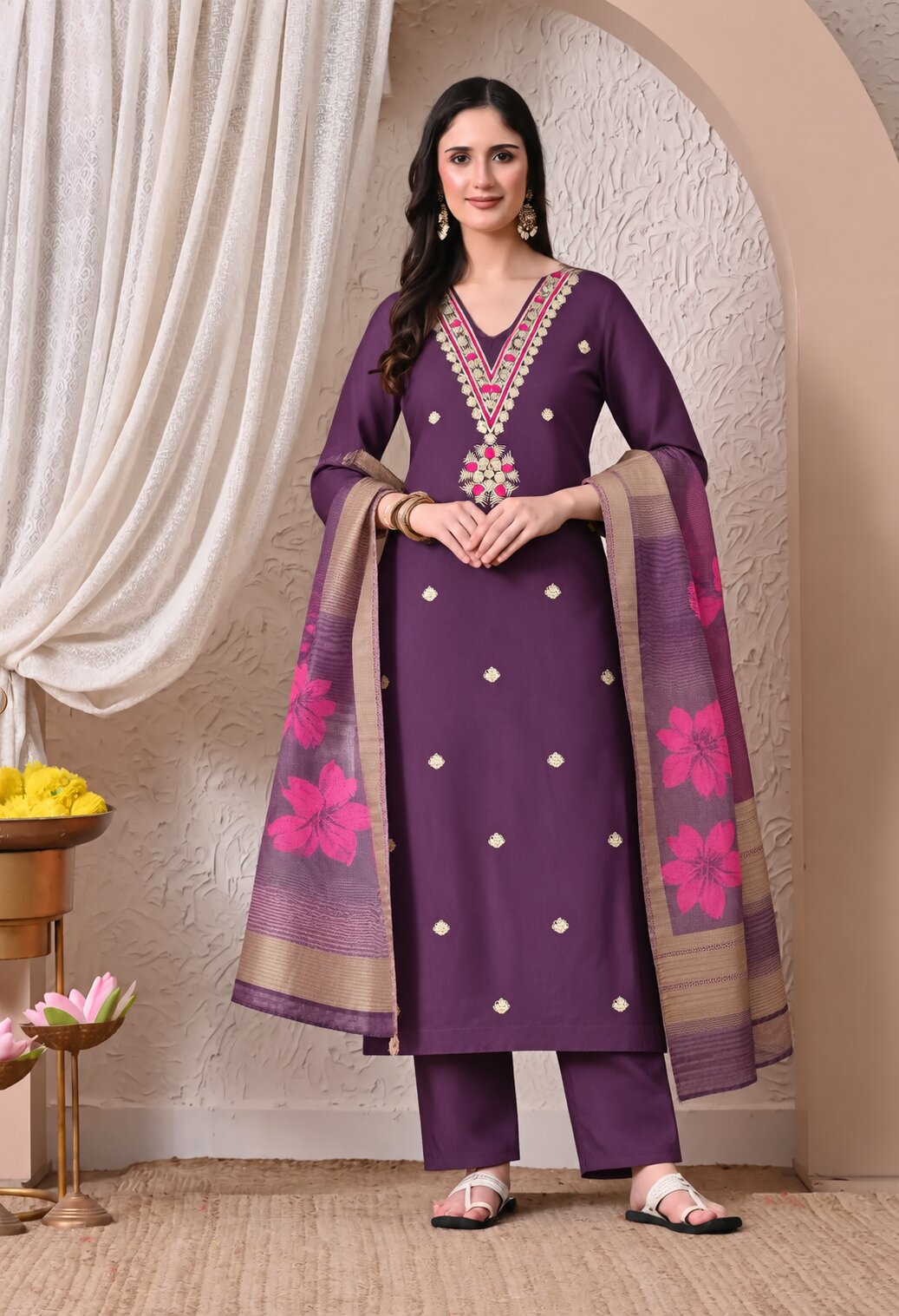 Purple embroidered salwar kameez suit set with matching floral dupatta, featuring a V-neck kurta with multicolour embroidery and small white motifs.