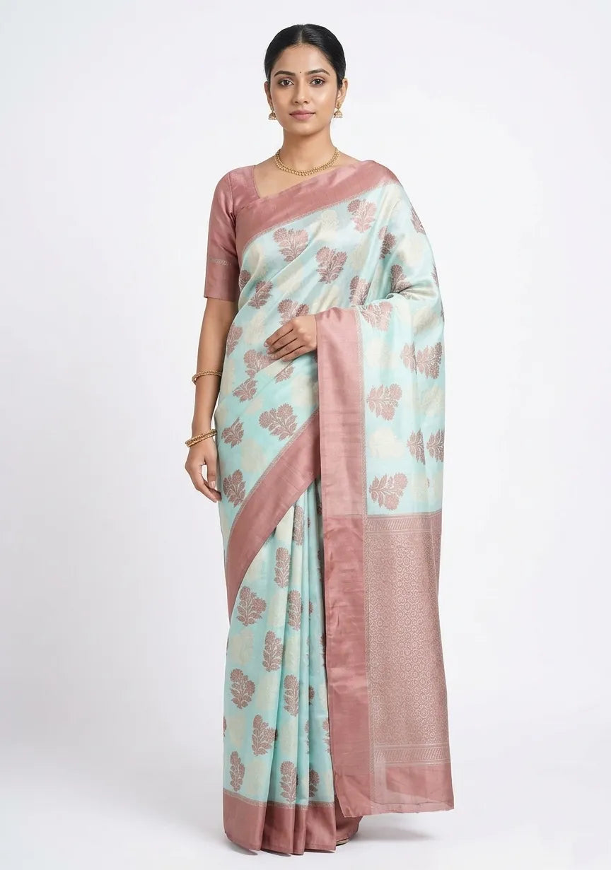 Model wearing a sea green and dusty pink silk blend Banarasi saree with large leaf-shaped woven motifs and a broad rose-gold toned zari border.