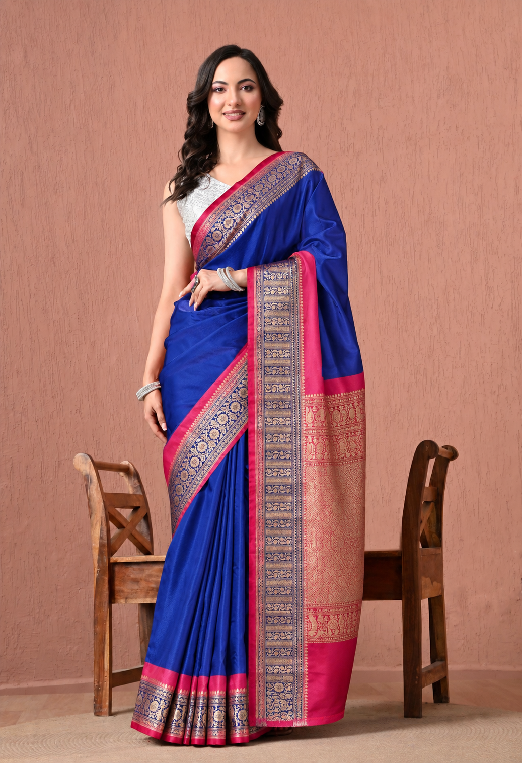 Woman wearing a royal blue silk blend saree with a magenta pink woven zari border.