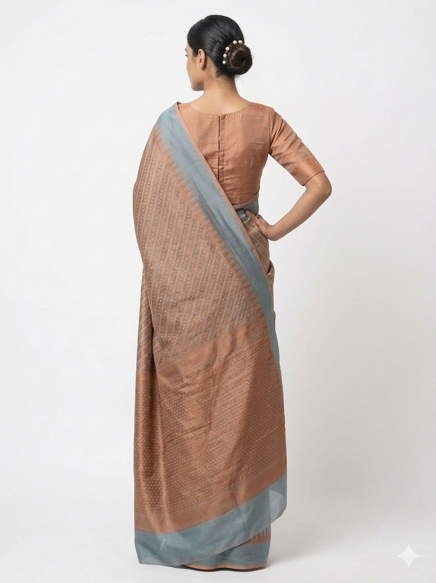 Rear view of a woman posing in a textured, copper-brown Banarasi silk saree with a contrasting grey border and a matching quarter-sleeve blouse against a white background.