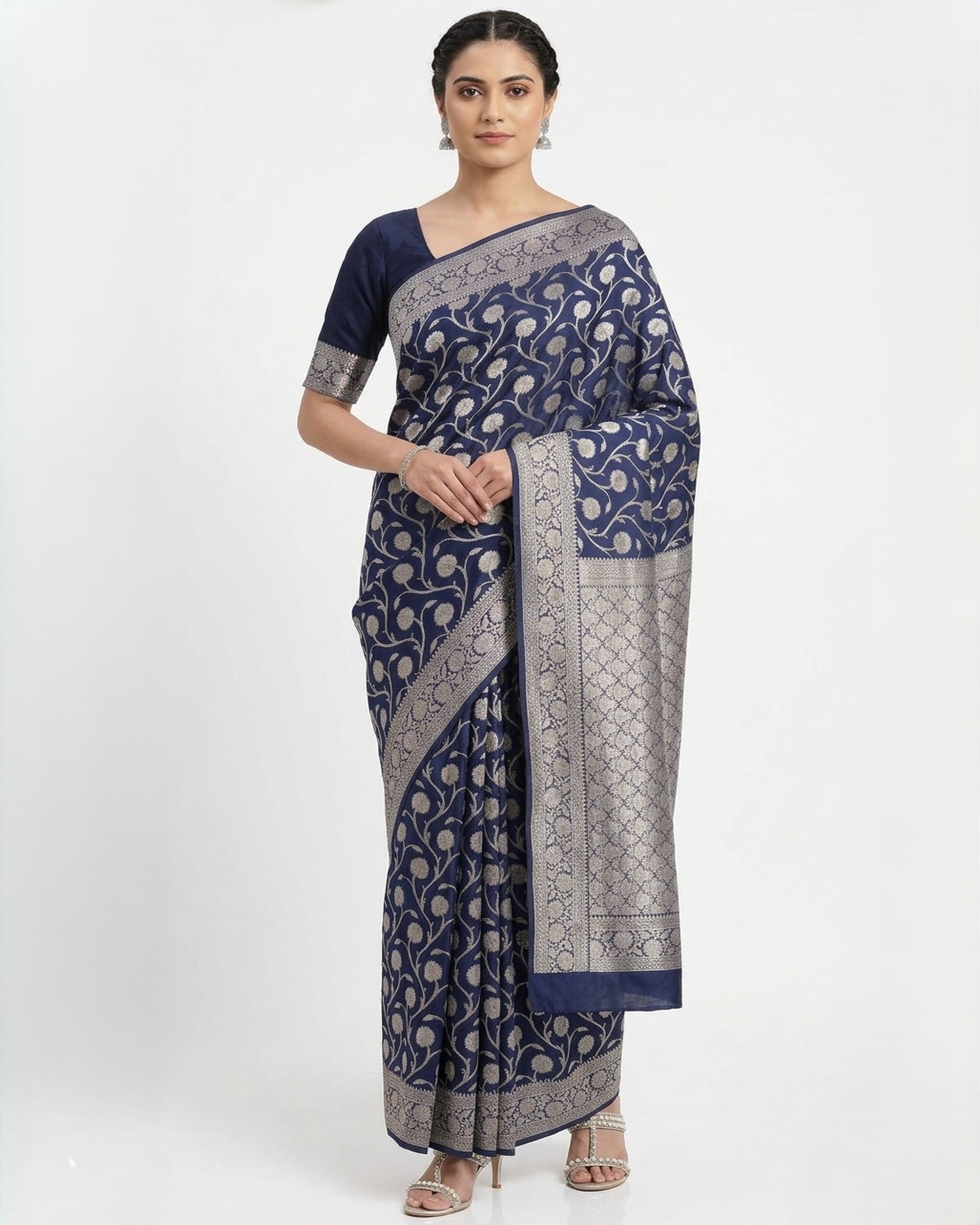 A woman wearing a navy blue Banarasi silk saree with silver floral patterns and a broad silver zari border, posed against a plain white background.