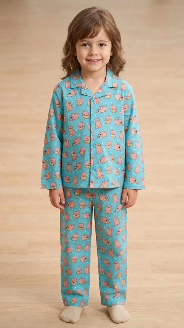 A young child wearing a turquoise cotton night suit with a pink puppy print and a button-front top.
