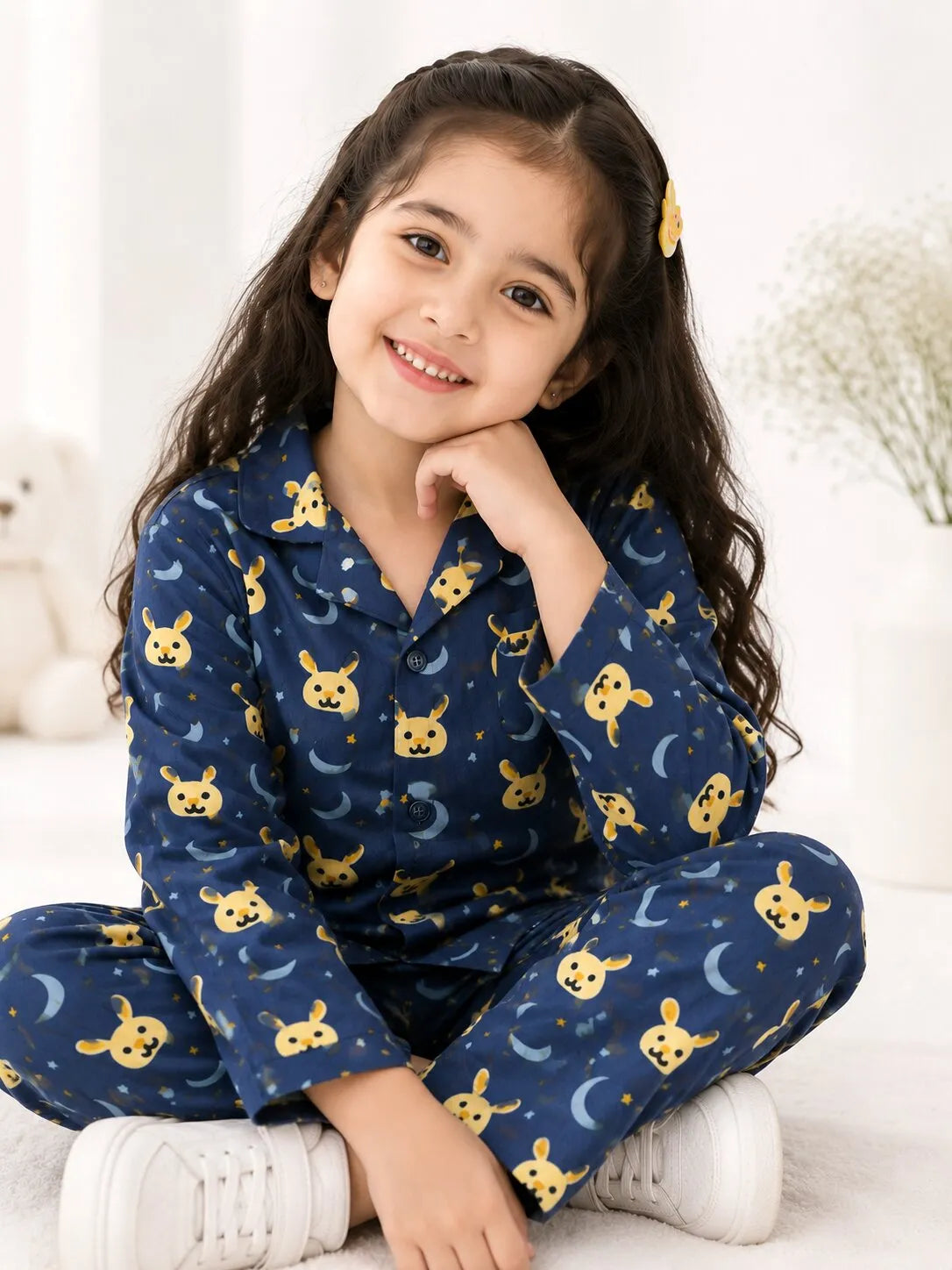 A young child wearing a navy blue cotton night suit with a yellow bunny and blue moon print.