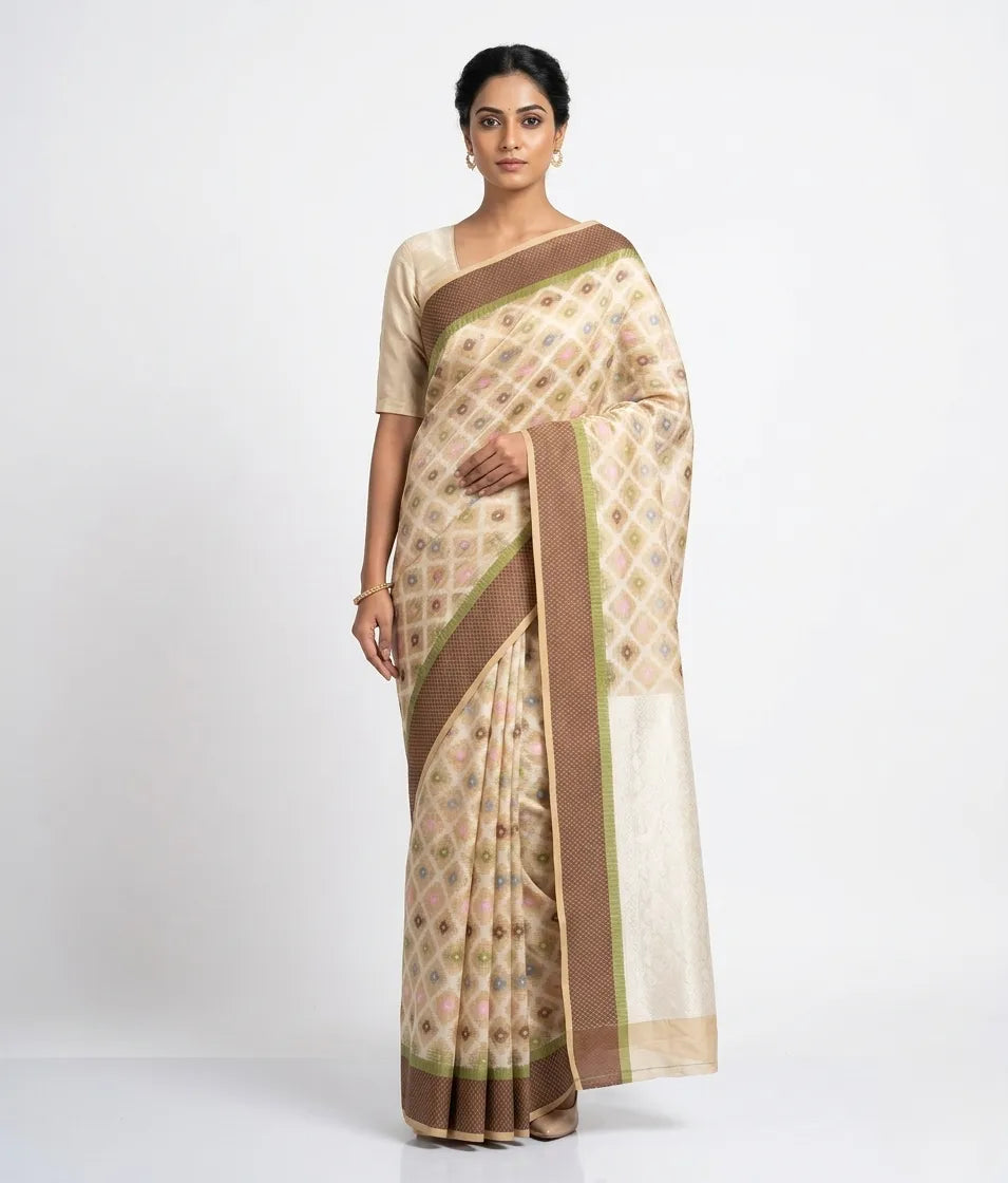 Elegant beige and brown Chanderi silk saree for women featuring a subtle geometric diamond print and a wide chocolate brown border with gold zari detailing. The model is wearing a matching beige short-sleeved blouse and gold jhumka earrings, presented against a clean white background.