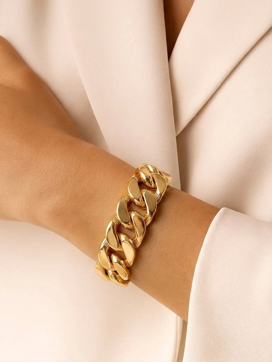 A high-polish, gold-tone chunky curb link bracelet shown at a close-up angle on a plain white surface.