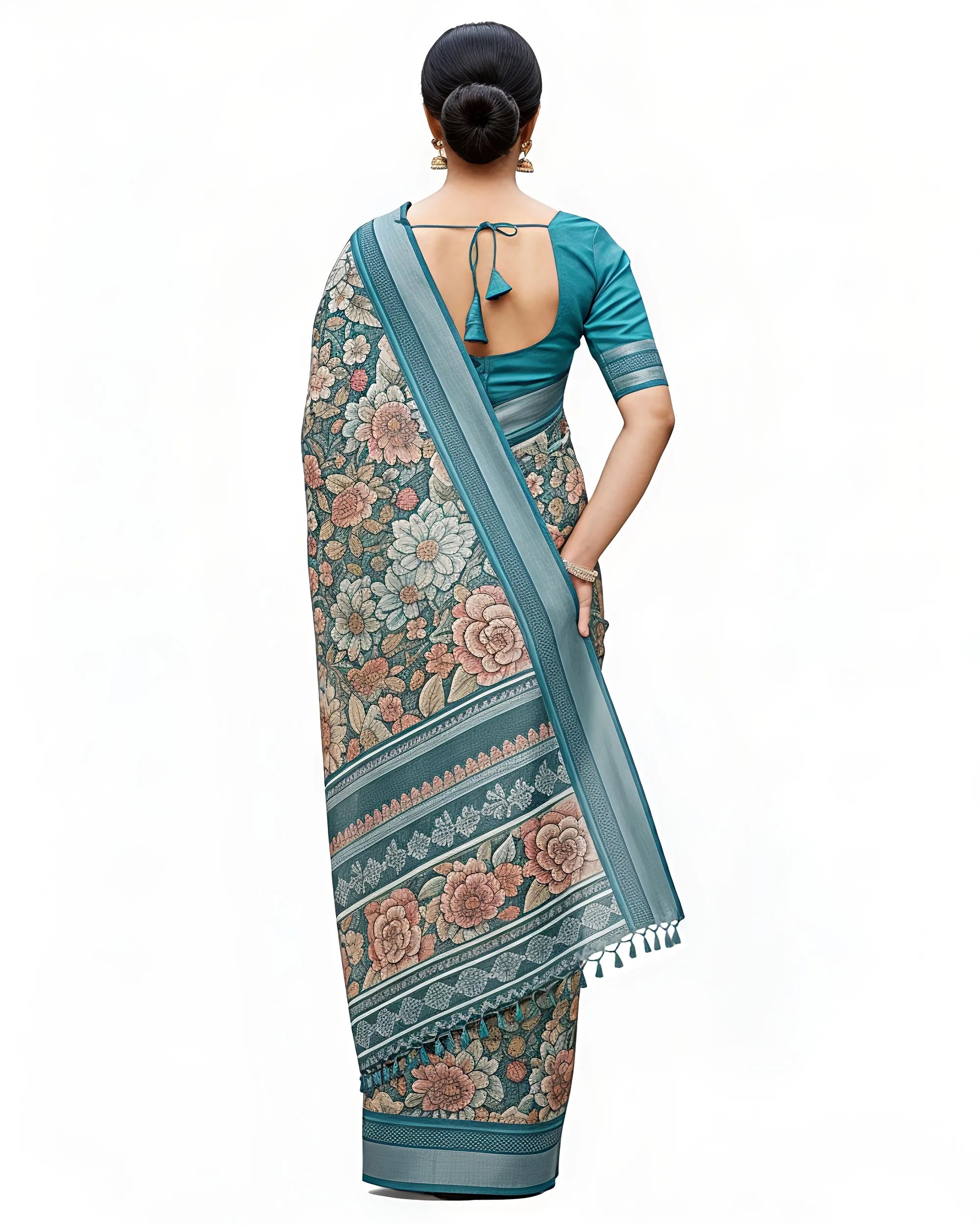 Back view of a teal green floral cotton saree. The matching teal blouse features .The saree's pallu is shown with intricate geometric border patterns and small fringe tassels at the end.