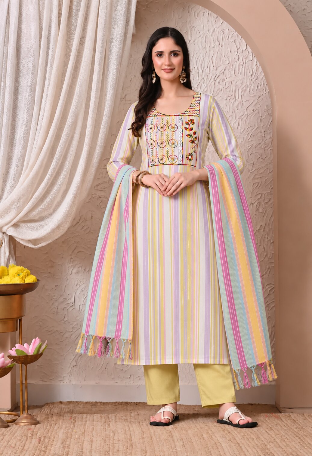 Pastel cream straight-fit kurta suit set featuring a multicolour embroidered square neckline, vertical pastel stripes in pink, yellow, and blue, paired with light yellow straight pants and a matching striped dupatta with tassel detailing.