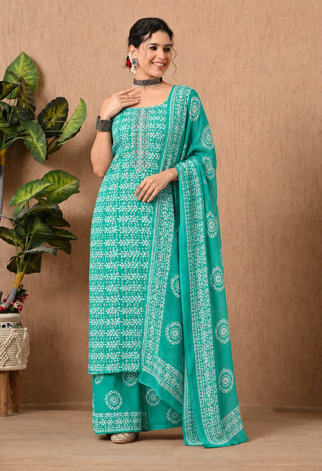 Teal green ethnic kurta suit with intricate white geometric and floral prints, round neckline, matching printed trousers, and a coordinating dupatta featuring traditional white motifs and decorative borders.