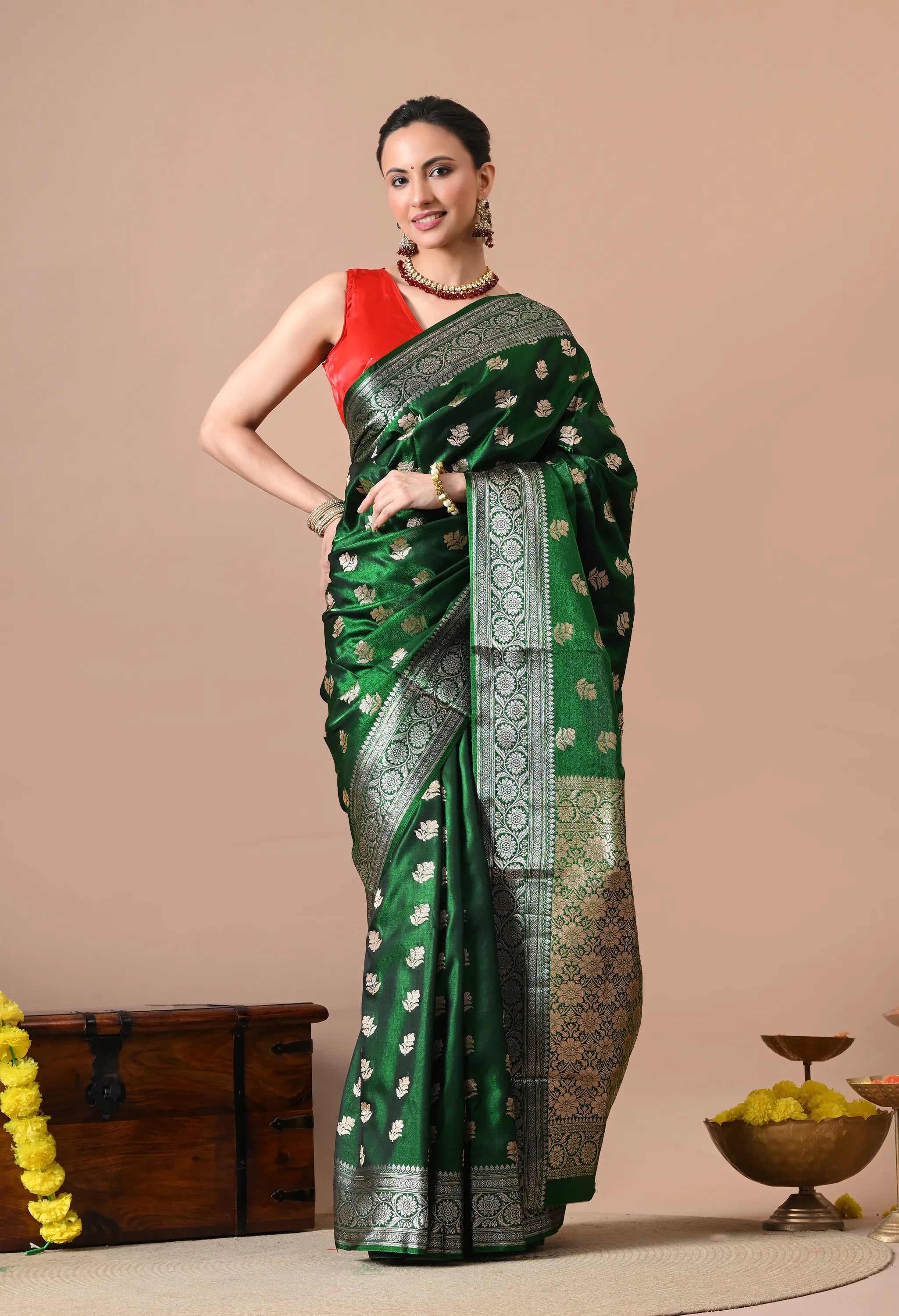 A woman wearing a luxurious bottle green and silver silk blend Banarasi saree with floral woven patterns.

