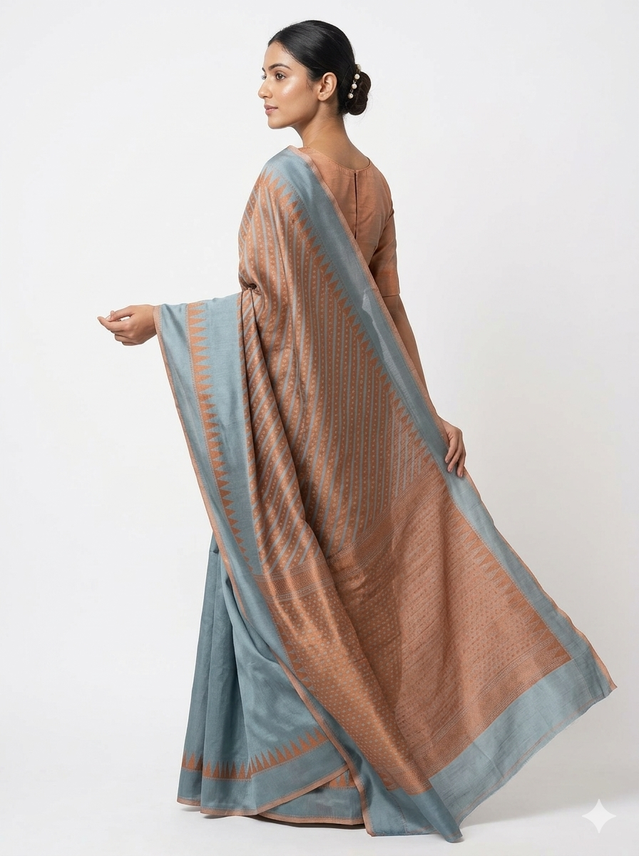Back view of a woman posing in a dual-toned silk blend saree with a textured copper-brown body and a contrasting muted blue-grey border on a plain white background.