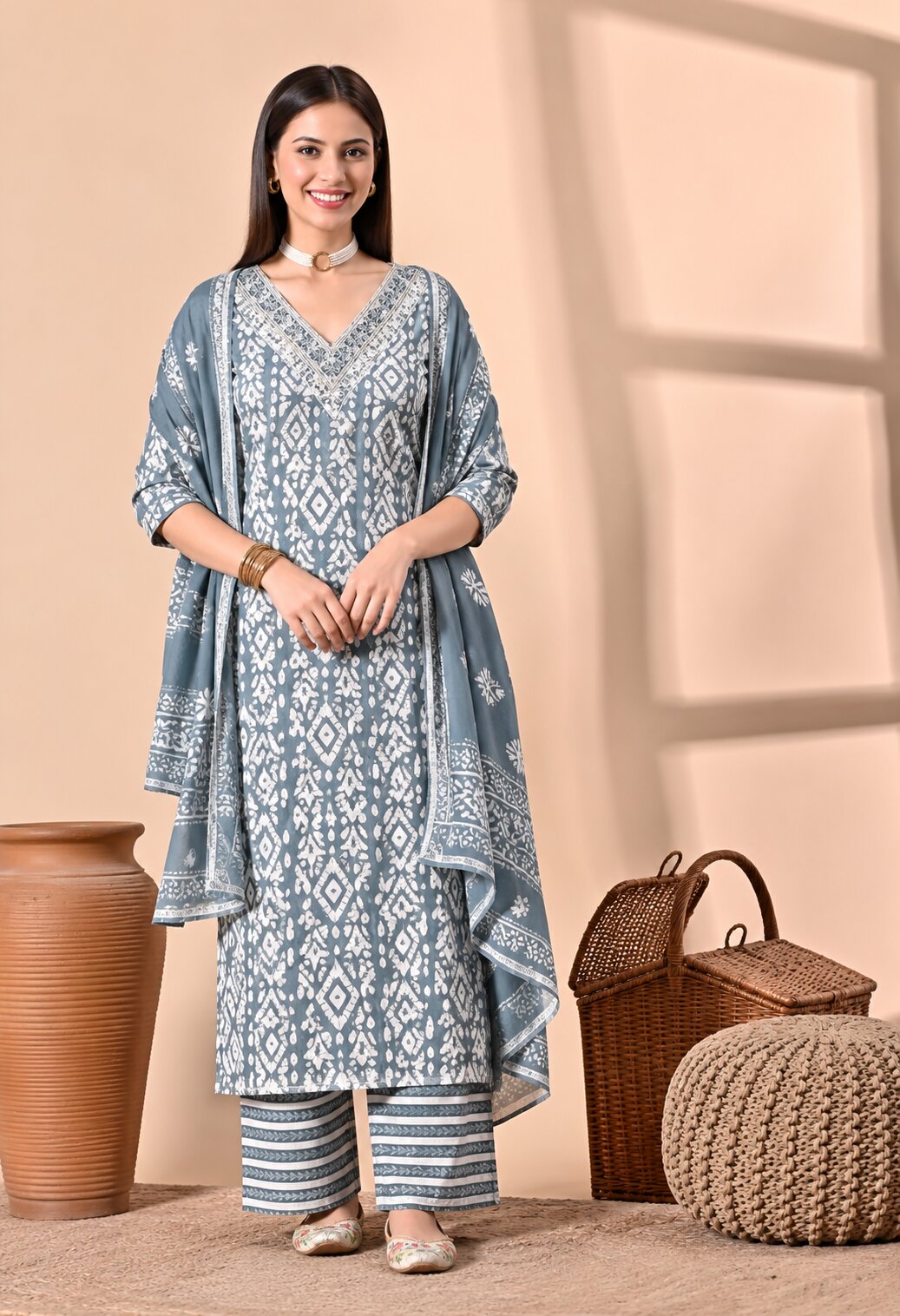 Grey ethnic kurta suit with white floral and geometric prints, V-neckline, matching striped trousers, and a coordinating dupatta with a printed border.