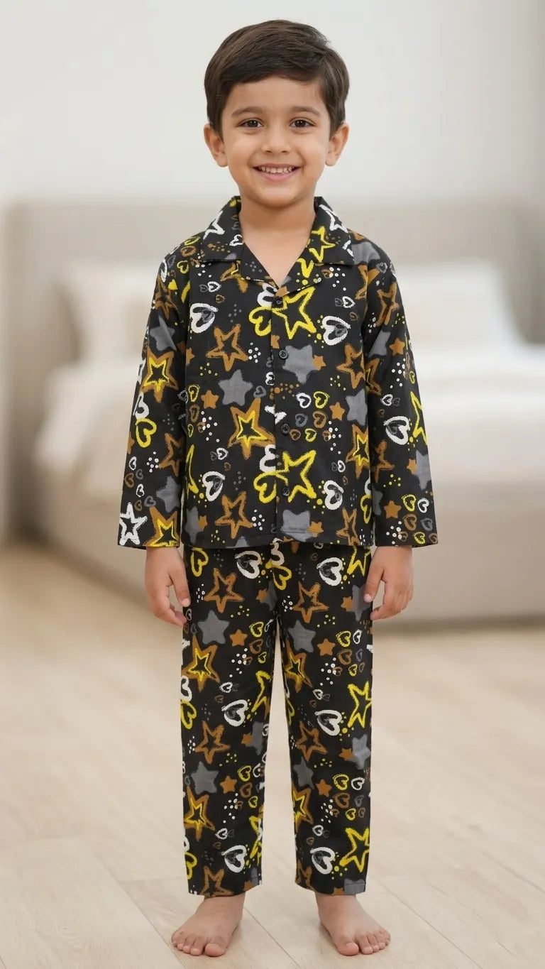 Young boy wearing a black cotton night suit featuring yellow and grey star prints with a notched collar shirt and matching pyjamas.

