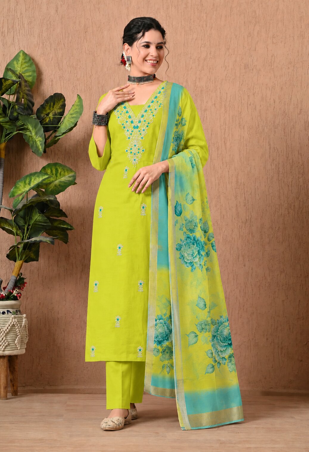 Lime green straight-cut kurta suit set with matching trousers and a turquoise blue floral dupatta, featuring a V-neckline with intricate blue embroidery, small floral motifs, and a decorative border on the dupatta.