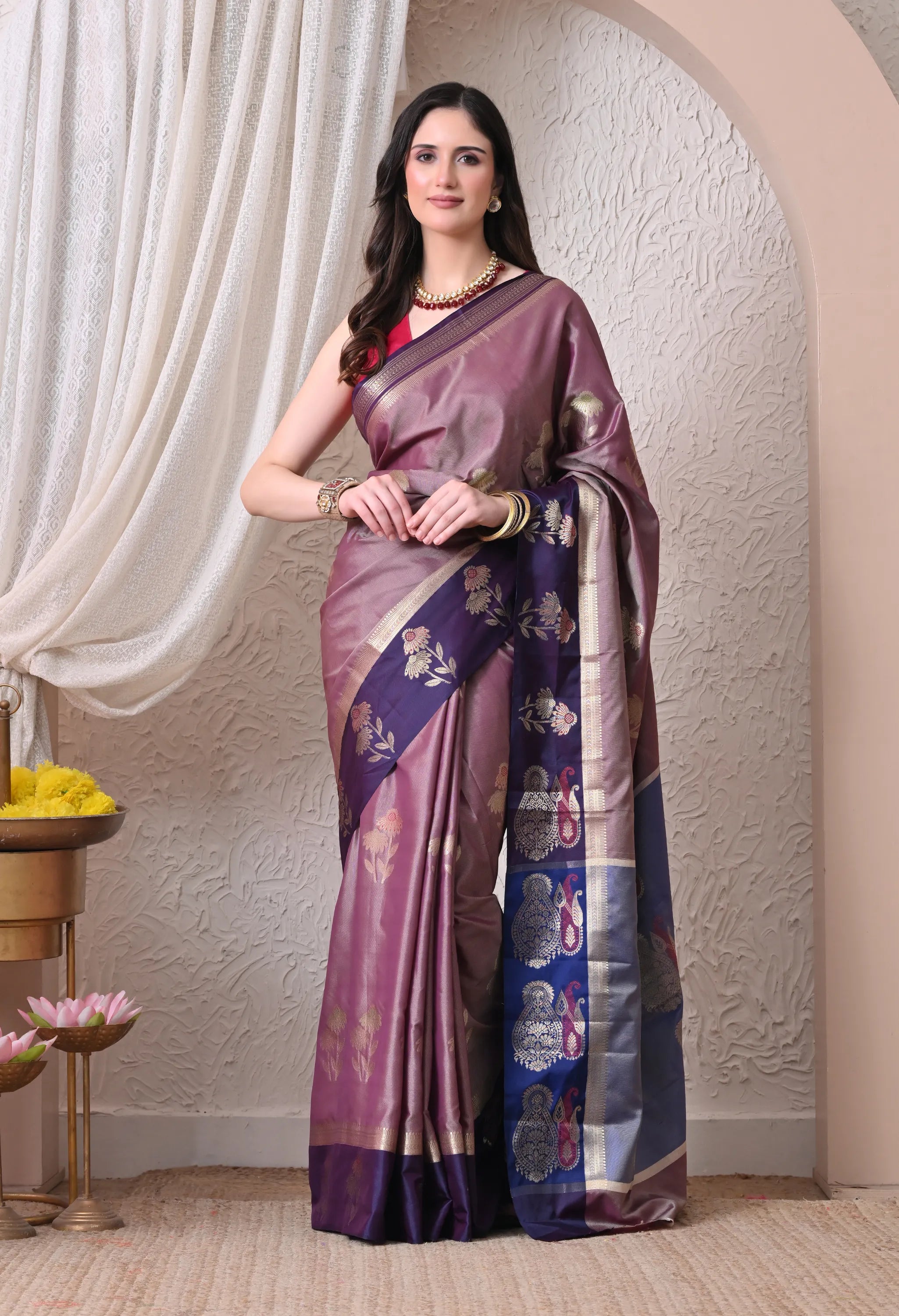 An elegant mauve silk blend saree featuring a deep purple contrast border and pallu adorned with golden zari floral and paisley motifs.
