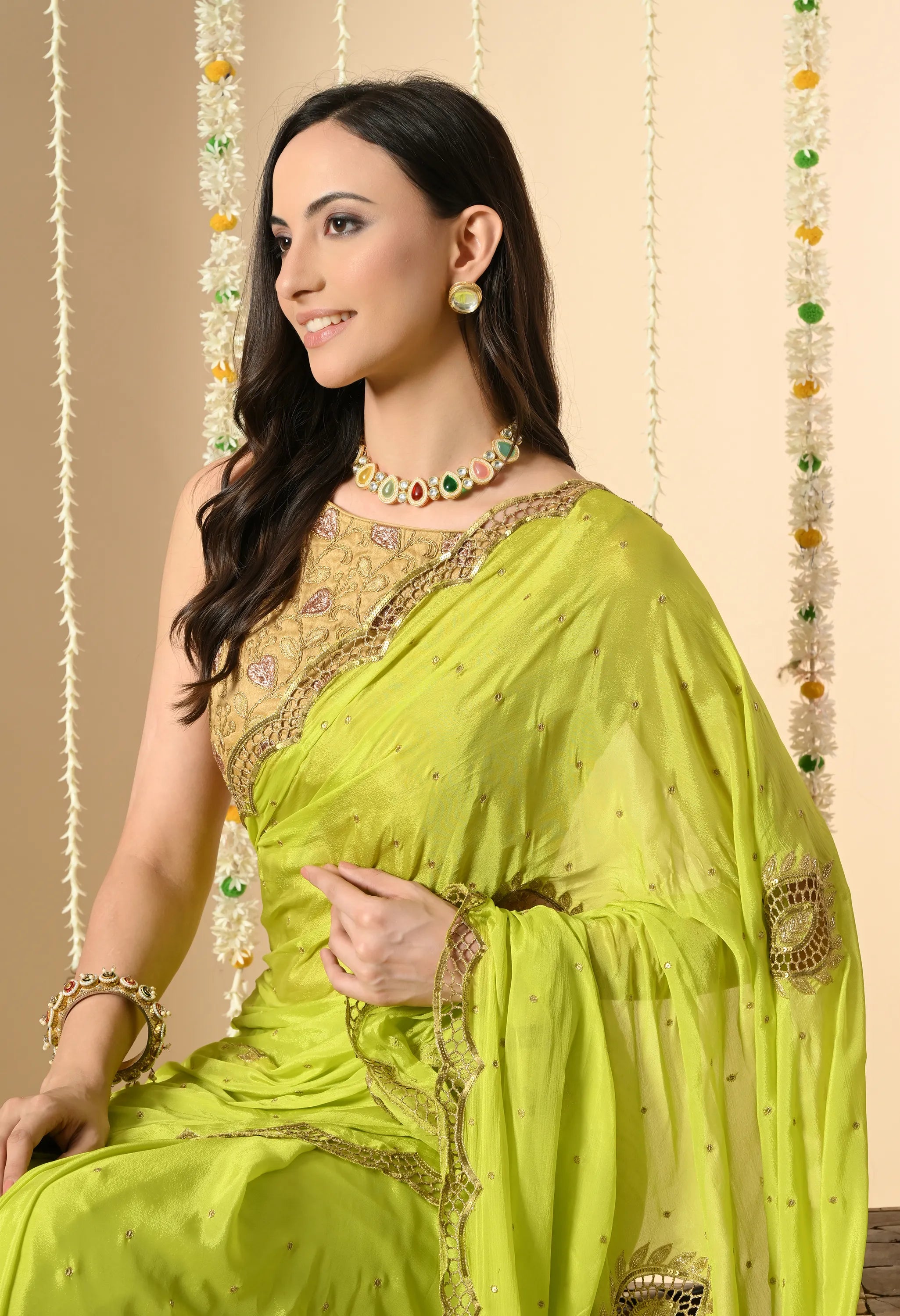 A model in a lime-green chiffon saree from The Weavers Shop by Raavi. The portrait highlights the gold blouse and the delicate scalloped border with cutwork, accessorised with a multicoloured necklace and matching earrings.