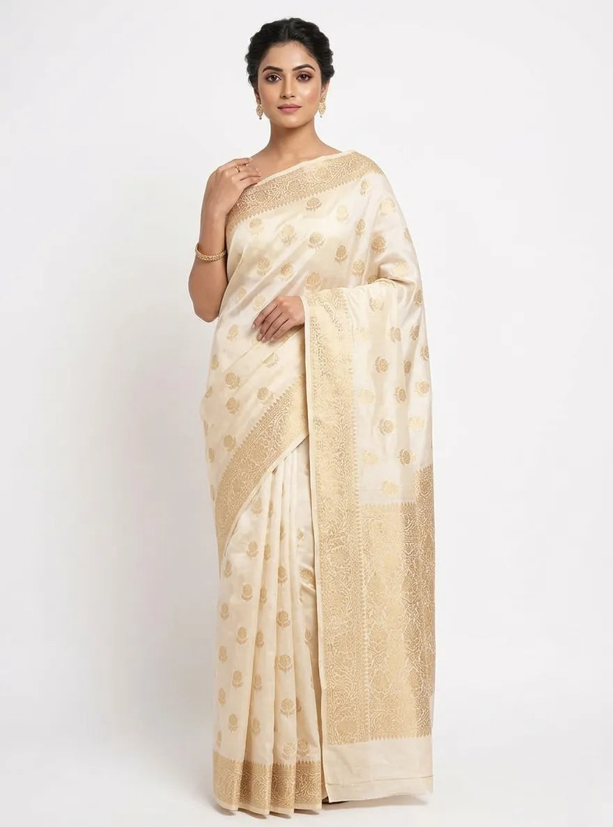 This saree is the epitome of "regal minimalism." Pair it with a contrasting maroon or deep emerald green velvet blouse for a modern twist, or keep it classic with the matching blouse. Complete the look with heavy gold jhumkas, a sleek middle-parted bun, and a bold red lip to let the cream-and-gold palette truly shine.