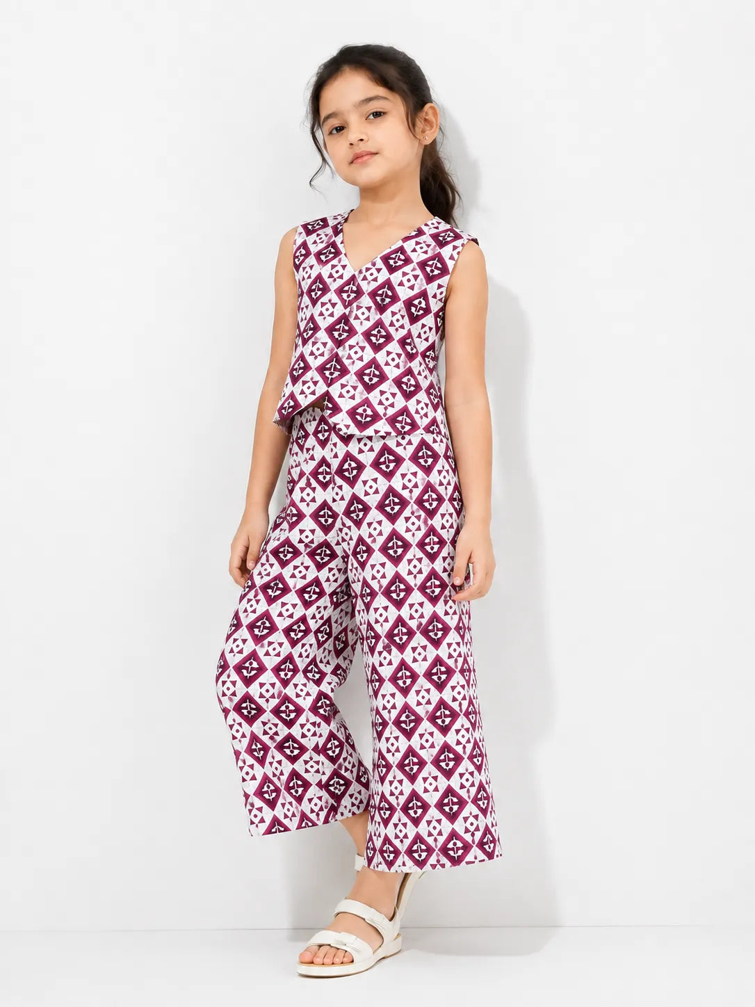 Young girl posing in a maroon and off-white geometric print co-ord set featuring a sleeveless vest and wide-leg trousers.
