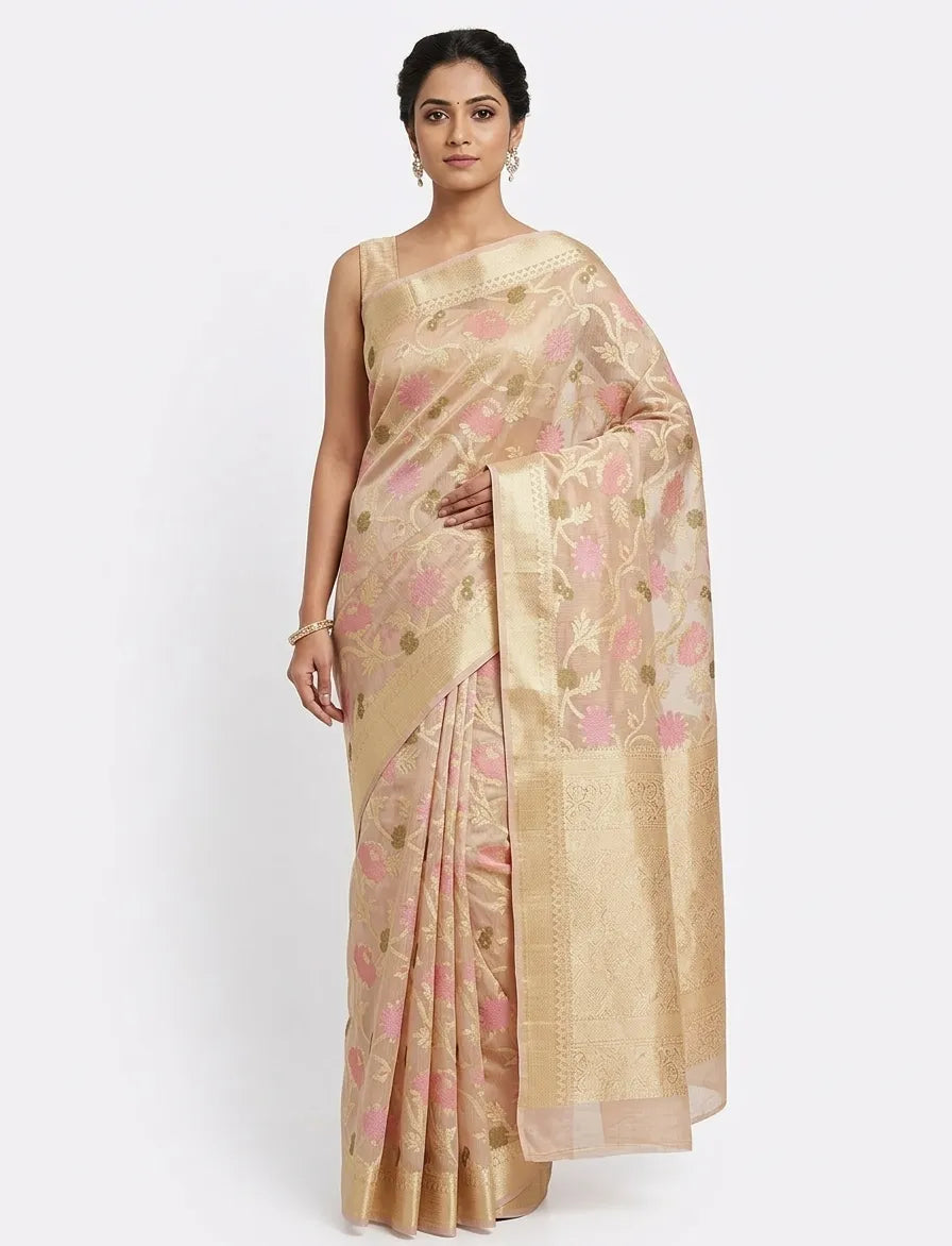 "Woman posing in a beige and pink floral Banarasi Chanderi saree with a gold zari border.

Product Details"
