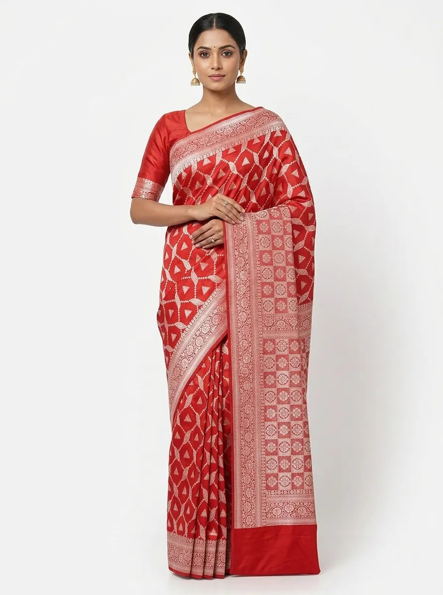 A woman posing in a vibrant red Banarasi Art Silk saree featuring an intricate all-over geometric woven pattern in gold-toned zari and a broad floral zari border.