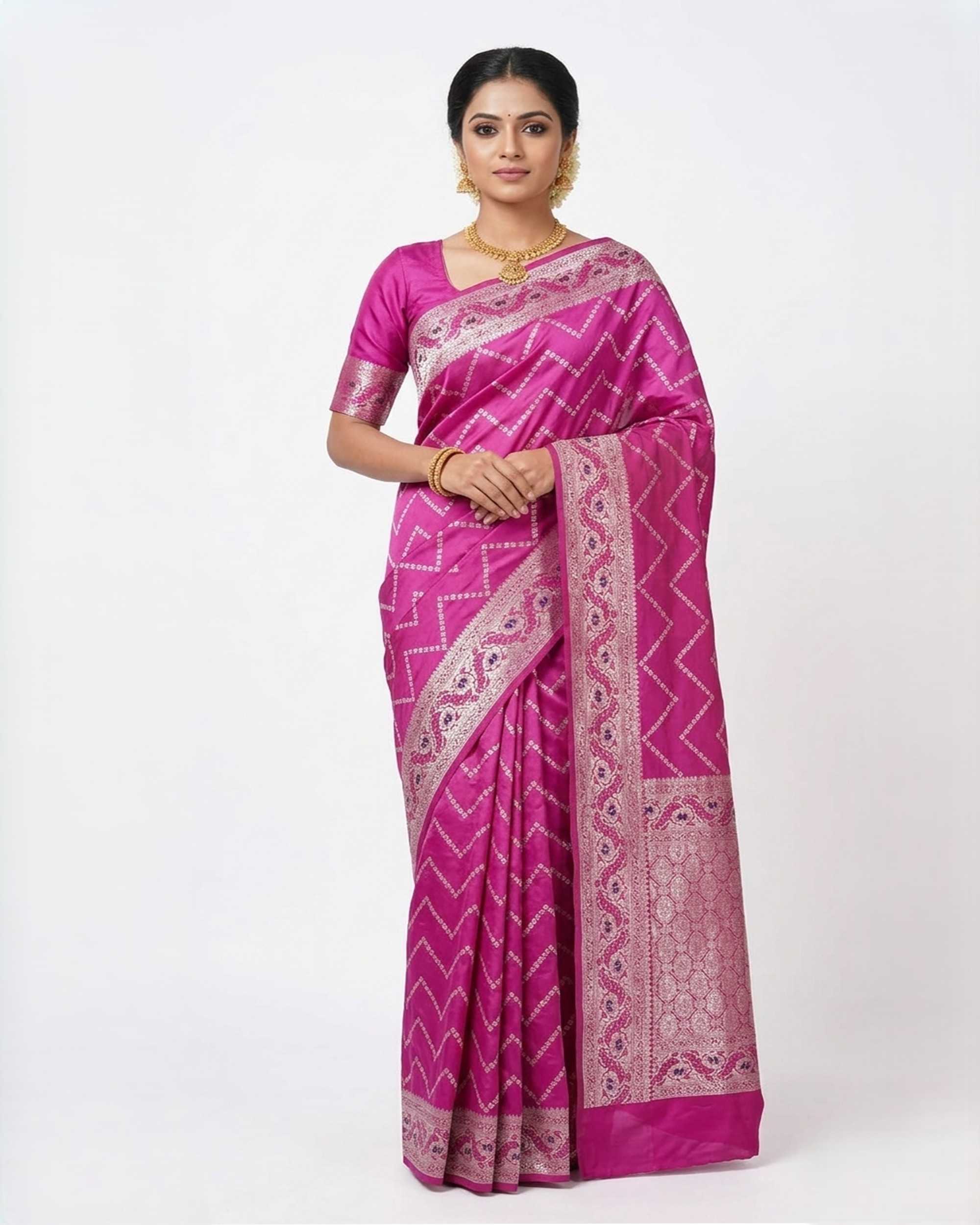 A woman wearing a bright magenta Banarasi silk saree featuring a silver zari grid pattern and a broad, intricate silver border, posed against a plain white background.