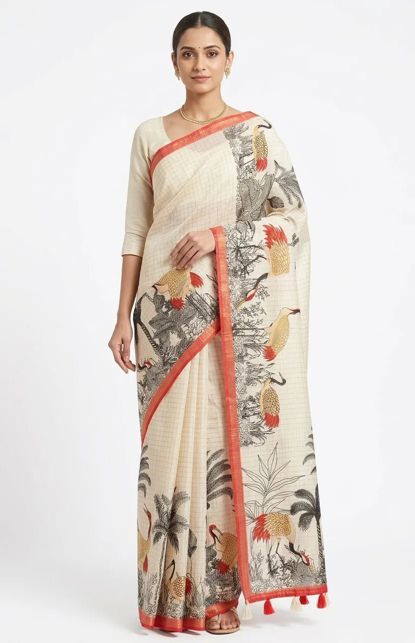 A woman posing in a cream-coloured cotton saree featuring black and ochre bird prints, palm tree motifs, and a thin red border with tassels.
