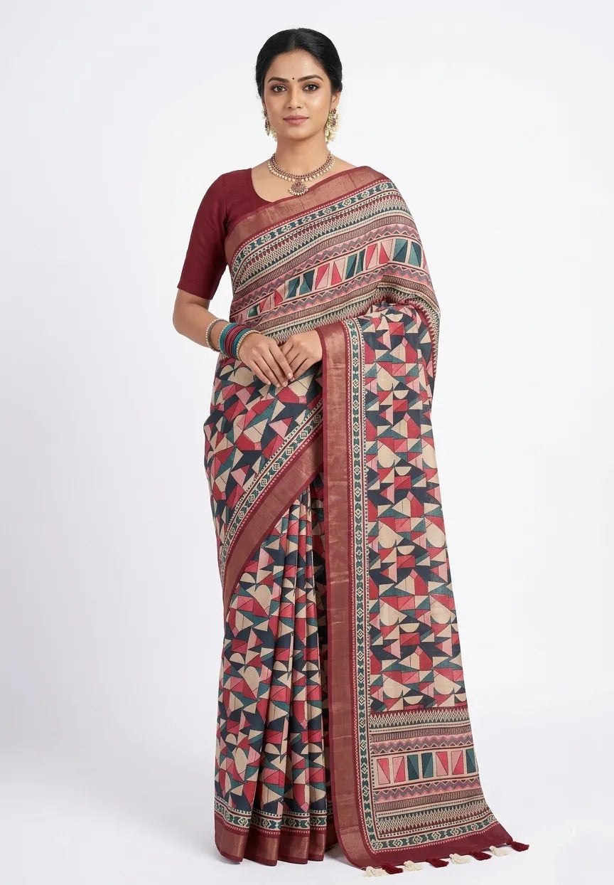 A woman wearing a maroon and beige silk blend saree with a multi-colored geometric triangular print, a metallic zari border, and tassel details.
