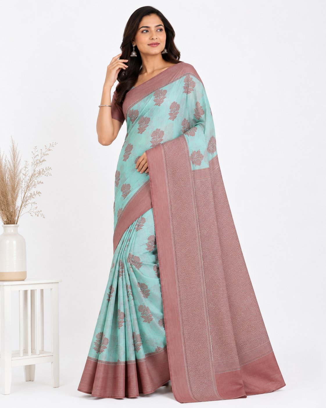 Model wearing a sea green and dusty pink silk blend Banarasi saree with large leaf-shaped woven motifs and a broad rose-gold toned zari border.
