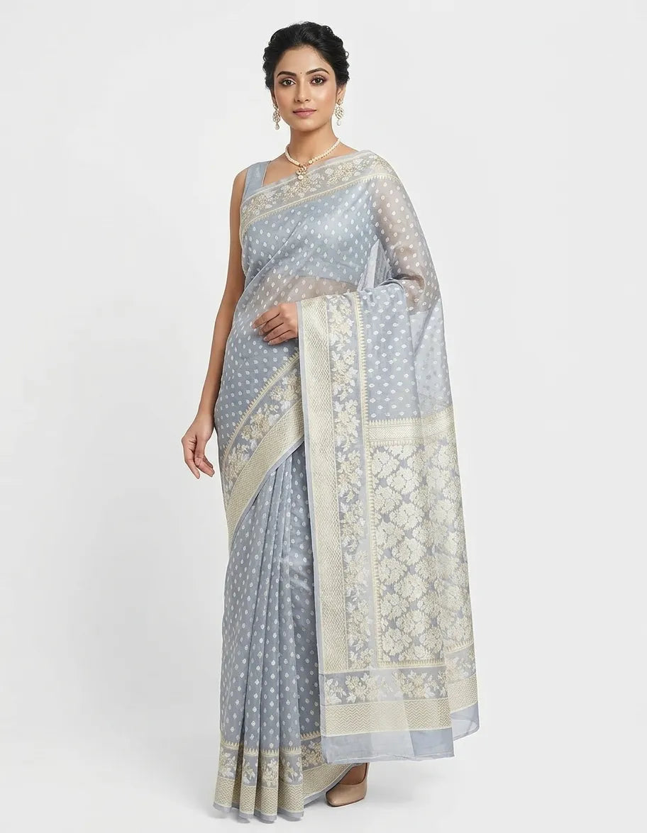 Model in a grey organza Banarasi saree featuring delicate off-white floral woven patterns, a sheer translucent texture, and a broad ornate border.
