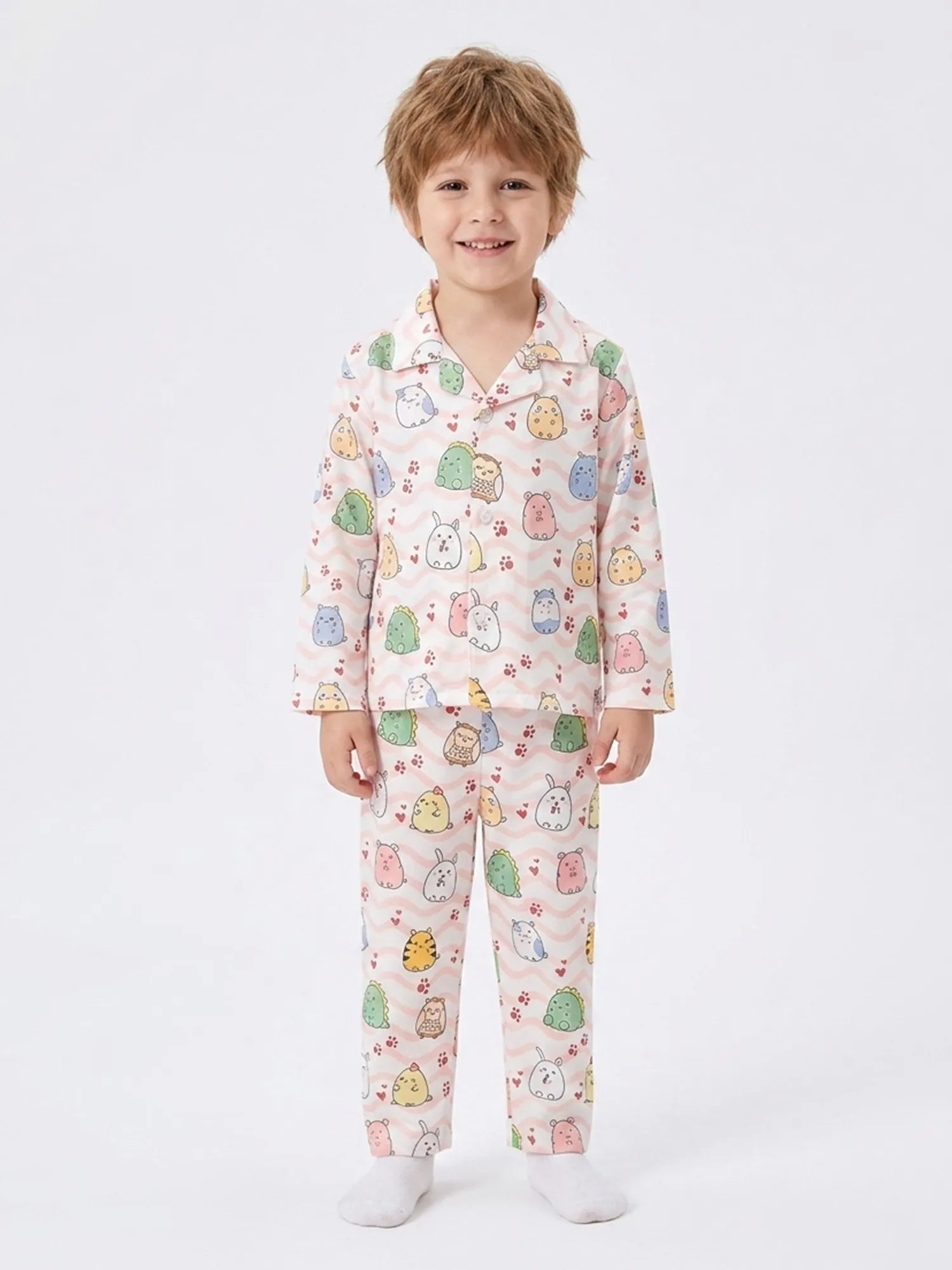 A young boy standing in a light pink satin night suit featuring a colorful animal and wavy line print.
