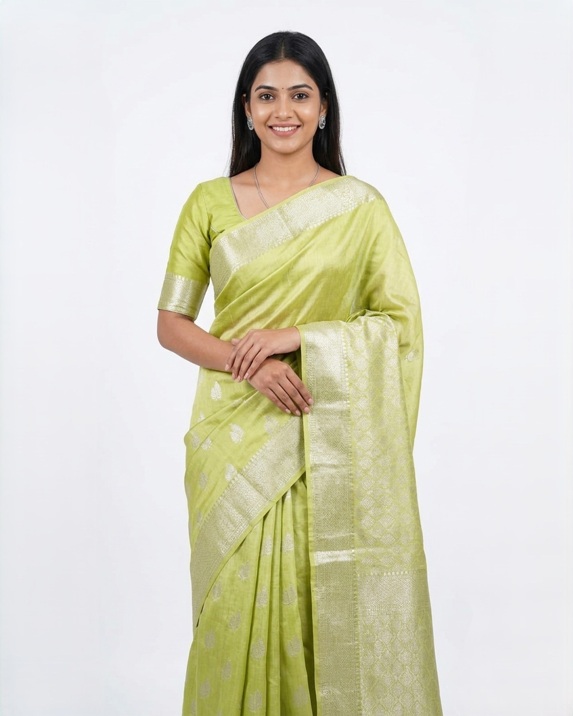A woman wearing a vibrant lime green Banarasi silk saree with silver zari floral patterns and a broad, intricate silver border, posed against a plain white background