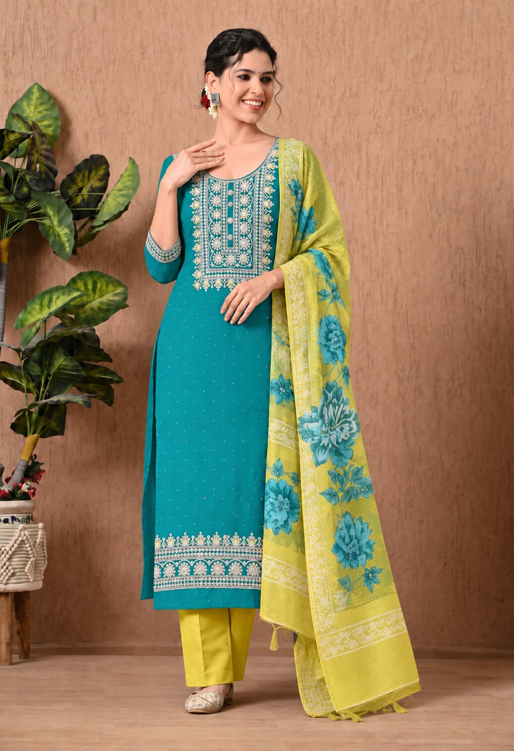 Teal blue straight-fit kurta suit set featuring intricate white embroidery on the neckline, front panel, and hem, paired with mustard yellow straight pants and a matching yellow dupatta adorned with blue floral prints and decorative borders.