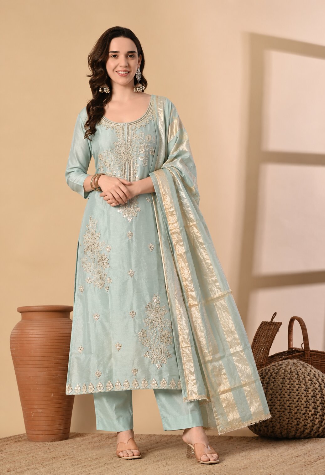 Light blue embroidered ethnic suit set featuring a straight kurta with intricate gold embroidery, matching trousers, and a coordinating dupatta with a broad golden woven border. Styled with three-quarter sleeves, a round neckline, and an elegant traditional design, perfect for festive occasions, weddings, and ethnic celebrations.