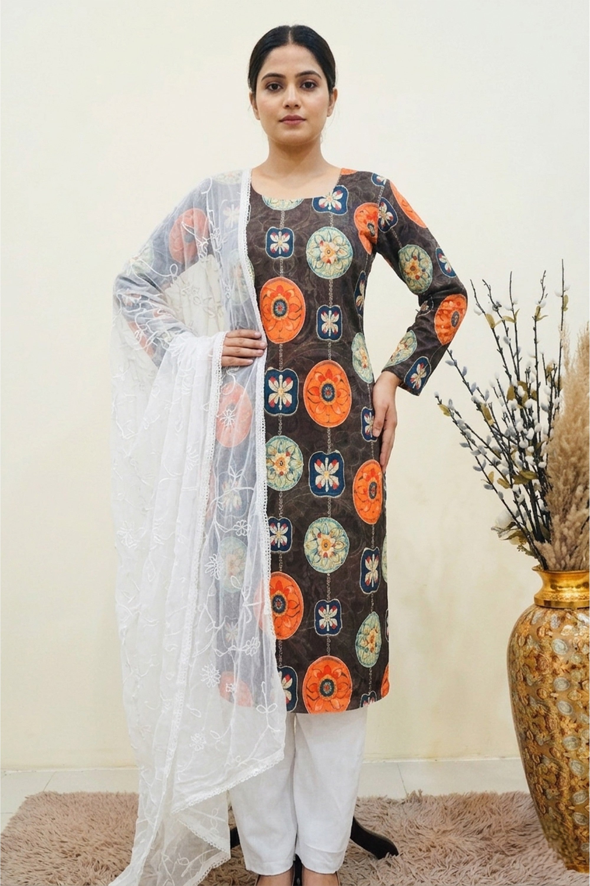 A charcoal cotton unstitched suit with orange and teal mandala prints, draped with a white embroidered organza dupatta on a mannequin.

