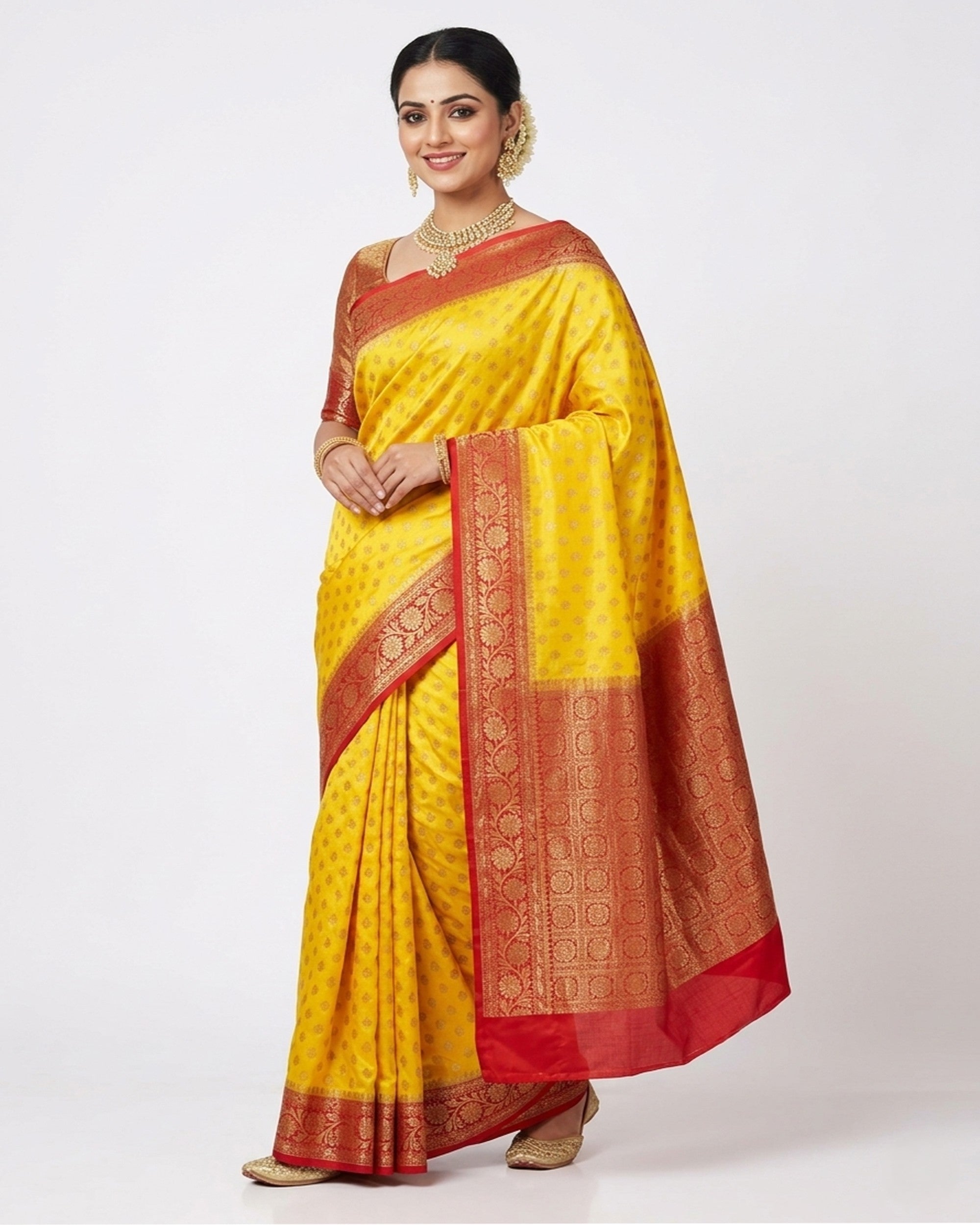 Woman in a vibrant yellow silk blend saree with a contrasting red and gold-toned zari border and decorative pallu.